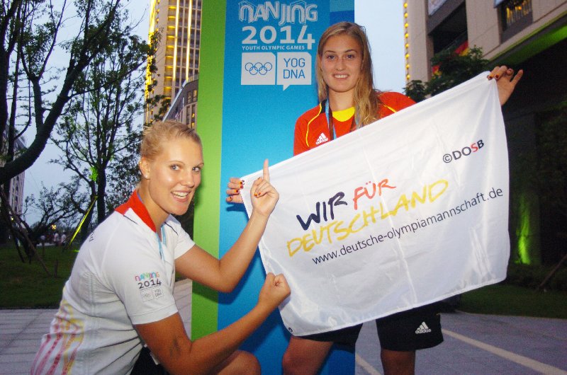 Olympische Jugendspiele Nanjing 2014: Lisa Arnholdt trägt deutsche Fahne - Beachvolleyballerin Lisa Arnholdt (re.) trägt die deutsche Fahne. Partnerin Sarah Schneider freute sich mit ihr - Copyright: DOSB